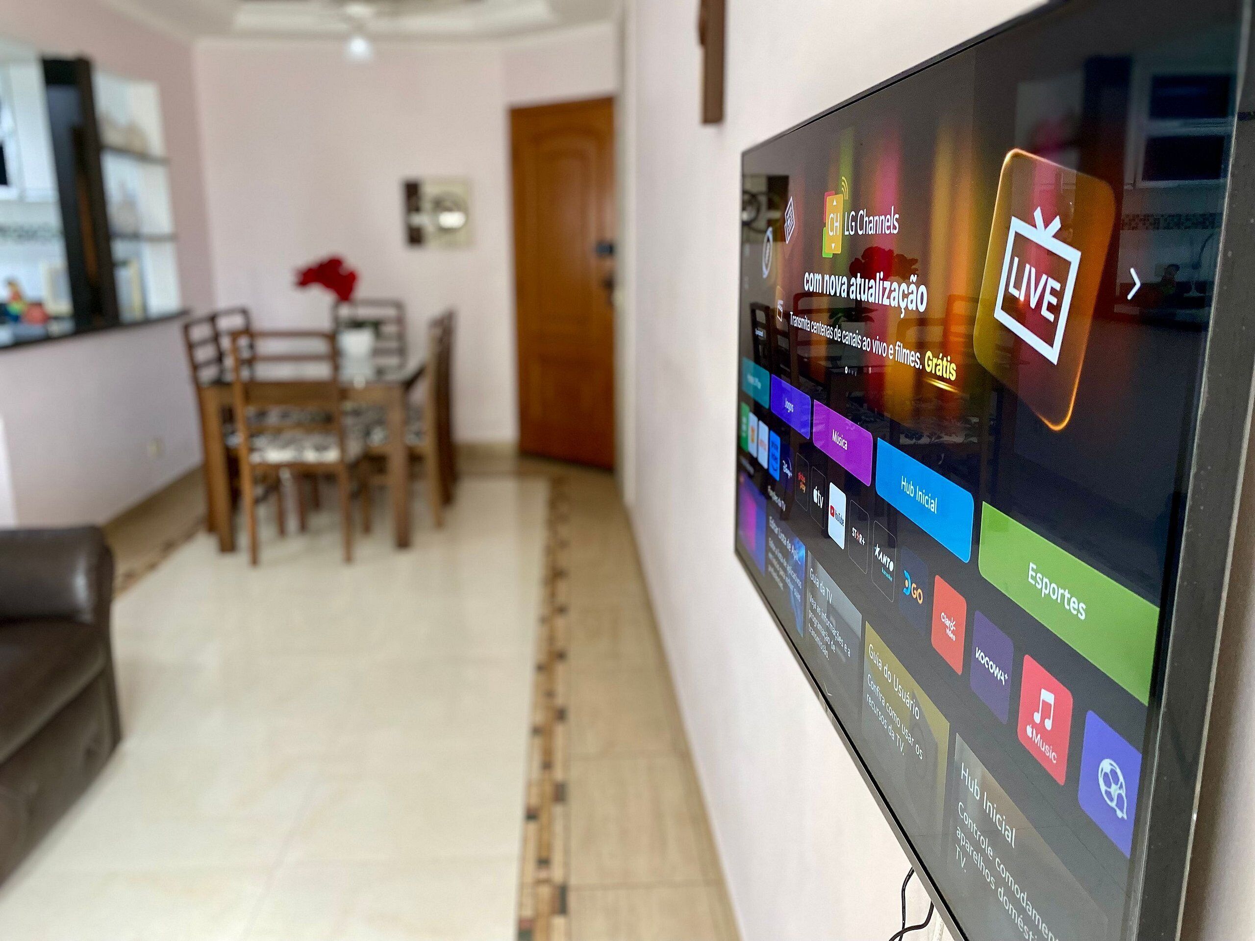 A flat-screen TV displaying a live channel interface with various app icons.