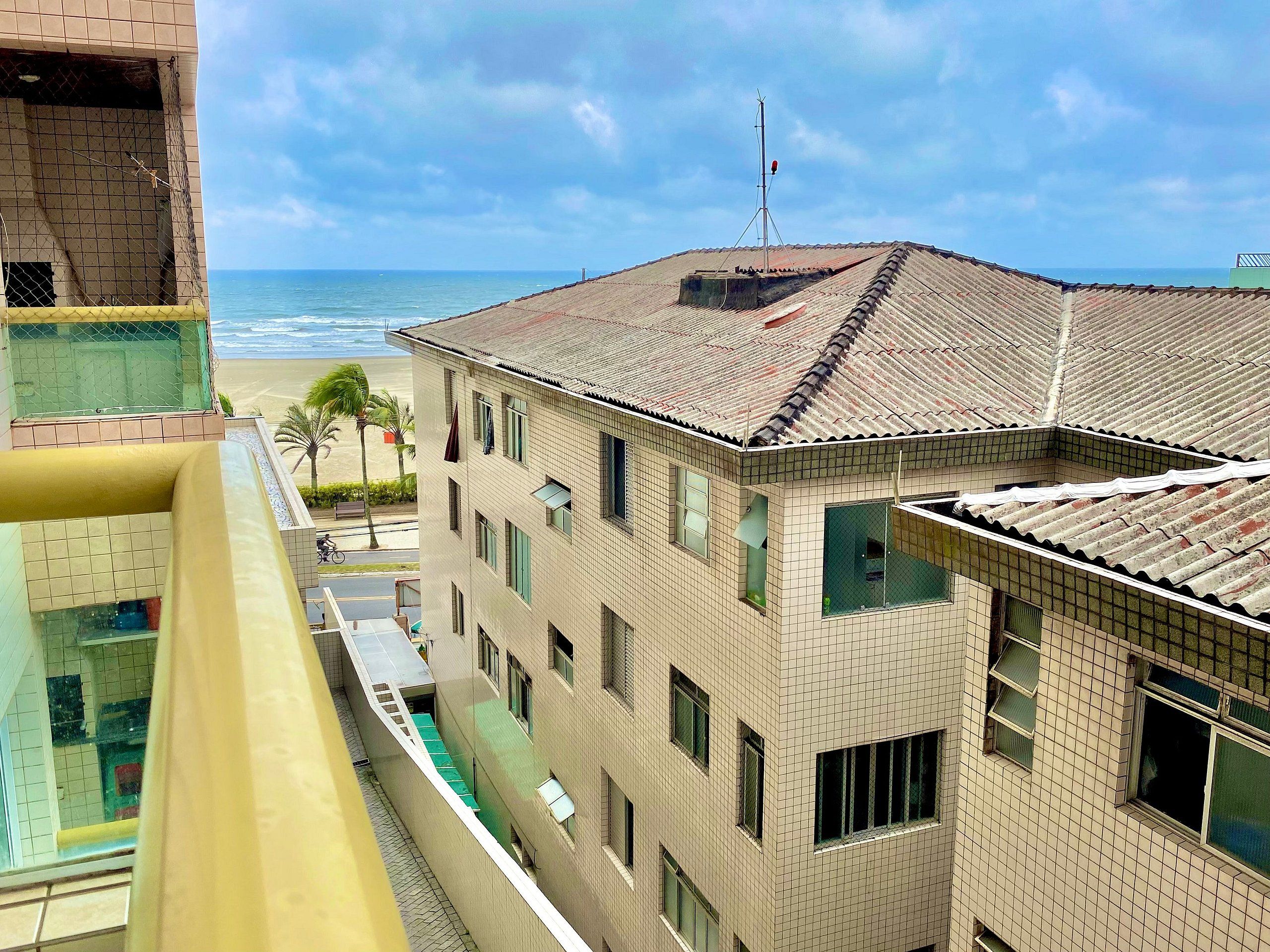 Um edifício de vários andares com telhado em cerâmica, varanda e vista para a praia.