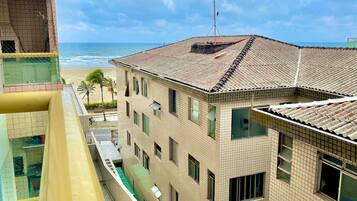 Um edifício de vários andares com telhado em cerâmica, varanda e vista para a praia.