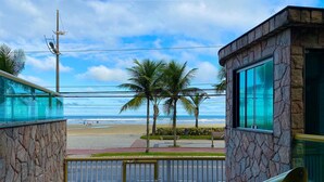 A view of a beach from a building with stone walls and a glass railing. - Residencial Blaia  (Praia Grande)