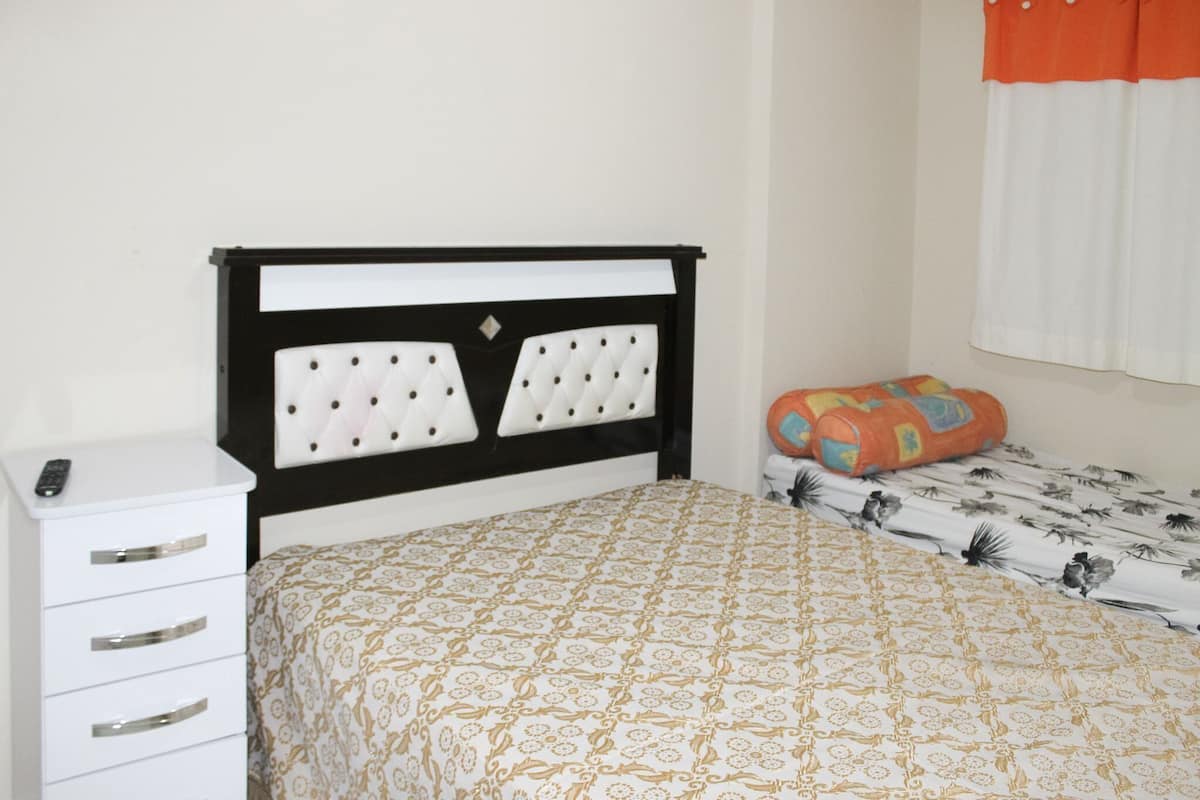 Quarto com cama, mesa de cabeceira e criado-mudo.