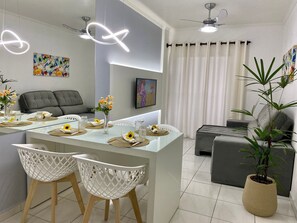 Un comedor moderno con una mesa de vidrio, sillas blancas y un jarrón con flores.