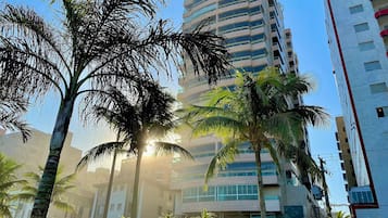 Un edificio alto con varios pisos, rodeado de palmeras y otra vegetación.