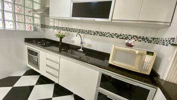 A kitchen with a black and white checkered floor, a microwave, a stove, and cabinets.