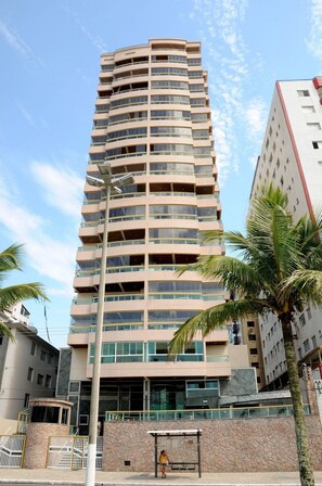 A multi-story building with a curved facade, balconies, and a gated entrance. - Residencial Blaia  (Praia Grande)