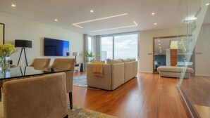 A modern living room with a sofa, a glass dining table, and a TV. - Casa com Vista Fabulosa Sobre a Baía do Funchal, a 5mt (Funchal)