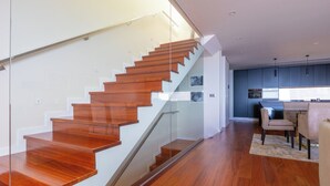 A modern interior with a wooden staircase, a kitchen area, and a dining space. - Casa com Vista Fabulosa Sobre a Baía do Funchal, a 5mt (Funchal)