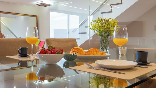 A modern dining area with a glass table, breakfast items, and a staircase in the background. - Casa com Vista Fabulosa Sobre a Baía do Funchal, a 5mt (Funchal)