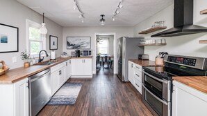 A modern kitchen with white cabinets, stainless steel appliances, and a wooden countertop. - Screened-in Hot Tub, Clean, 5 min to LU + Shopping! (Lynchburg)