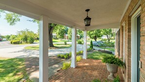 A covered porch with a brick floor, white columns, and a hanging lantern. - Screened-in Hot Tub, Clean, 5 min to LU + Shopping! (Lynchburg)