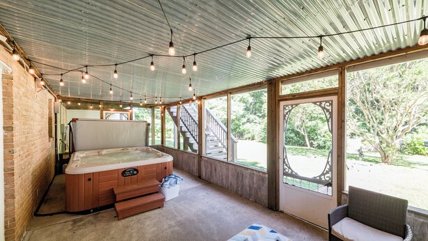 A hot tub in a covered outdoor area with a wooden deck and large windows. - Screened-in Hot Tub, Clean, 5 min to LU + Shopping! (Lynchburg)