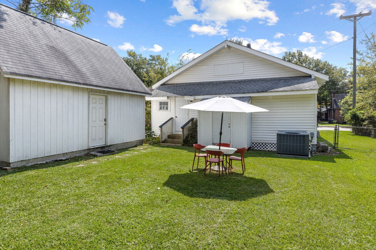 Une maison blanche d’un seul étage, dotée d’un patio couvert et d’un petit garage attenant.