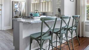 A modern kitchen with a central island, stainless steel appliances, and a large window with shutters.