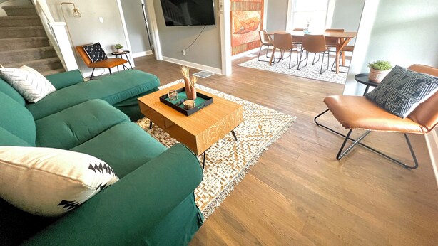 Una sala de estar moderna con un sofá seccional verde, una mesa de centro de madera y un sillón de cuero.