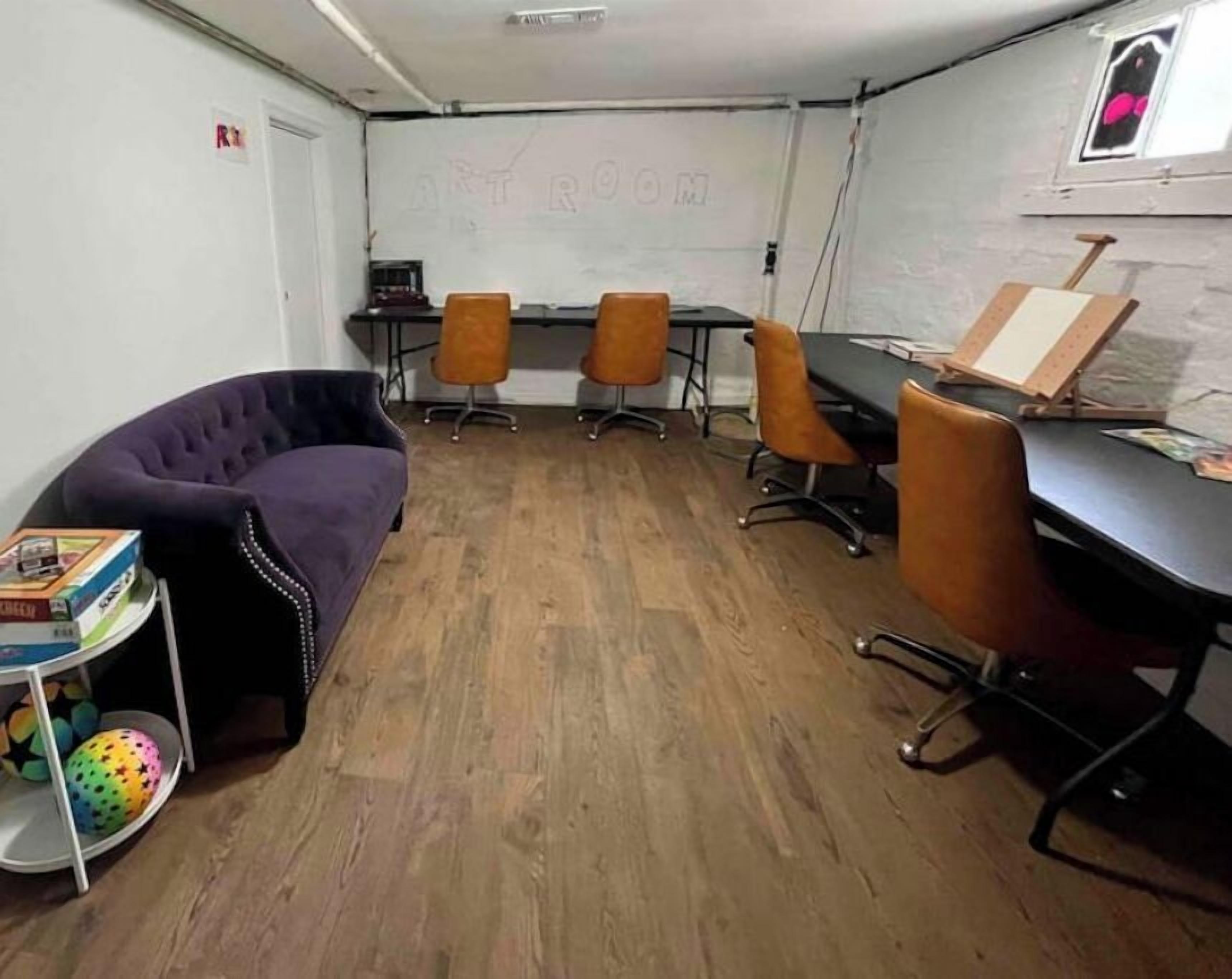 Una sala de conferencias con un sofá púrpura, dos mesas con sillas y una pizarra.