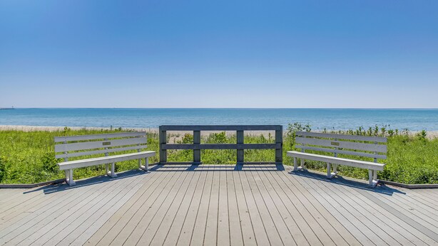 A wooden deck with two white benches facing a beach. - Algoma Victorian - Steps to Lake Michigan! (Algoma)