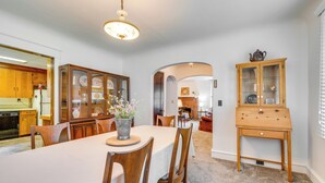 A dining area with a table set for four, surrounded by wooden chairs. A vase with flowers is on the table, and there is a wooden cabinet with glass doors to the right. - 8 Mi to Elk Mountain Ski Resort: Clifford Home! (Clifford)