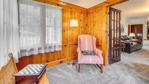 A cozy room with a wooden paneled wall, a plaid armchair, a chessboard, and a lamp. - 8 Mi to Elk Mountain Ski Resort: Clifford Home! (Clifford)