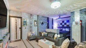 A modern living room with a sofa, coffee table, and a bed with a patterned headboard.