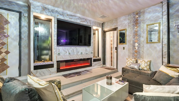 A modern living room with a fireplace, comfortable seating, and a large TV.