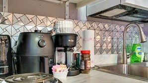 A kitchen with a coffee maker, a kettle, a jar of coffee creamer, and a roll of paper towels.