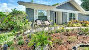 A modern house with a covered patio, outdoor seating, and a well-maintained garden.