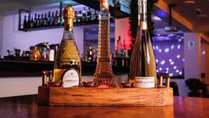 A wooden wine rack holding three bottles of wine.