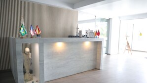 A reception desk with a modern design, featuring a glass display case with a sculpture and flags.
