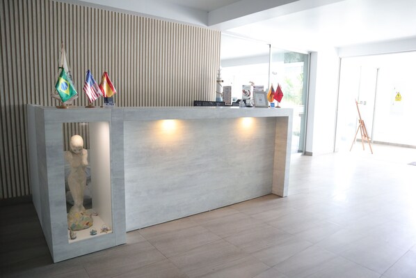 Un mostrador de recepción de diseño moderno, con una vitrina de cristal que exhibe una escultura y banderas.