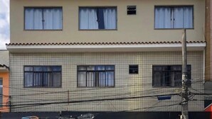 A two-story building with a tiled facade and multiple windows with curtains. - POUSADA HD (Nova Friburgo)