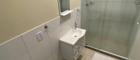 Une salle de bain équipée d’un WC, d’un lavabo, d’un miroir et d’une douche à parois en verre.