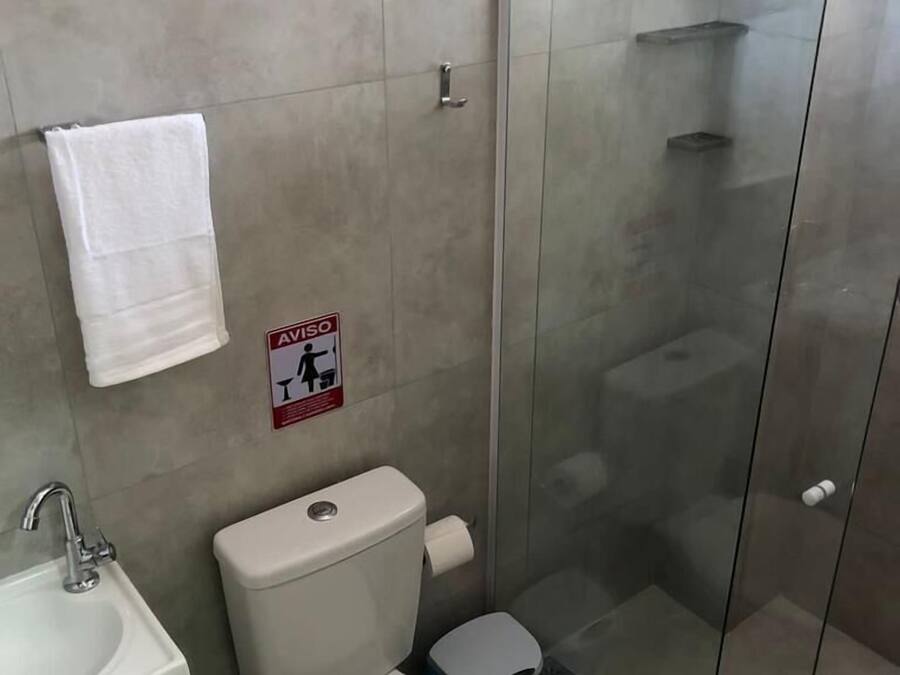 A bathroom with a toilet, sink, and glass shower enclosure.