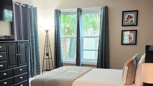 Une chambre à coucher avec un grand lit, une armoire, un bureau, une lampe et une fenêtre avec des rideaux.