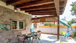 A covered patio with stone walls, a table with chairs, and a view of a residential area.