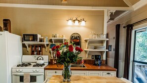Une cuisine dotée d’un îlot central, d’appareils électroménagers blancs et offrant une vue par une fenêtre.