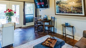 Un vaste salon doté d’un haut plafond, d’un coin repas et d’un téléviseur fixé au mur.