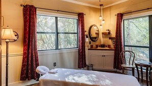 Une chambre à coucher avec un lit, un ventilateur de plafond, une fenêtre, un miroir, une chaise et une table.
