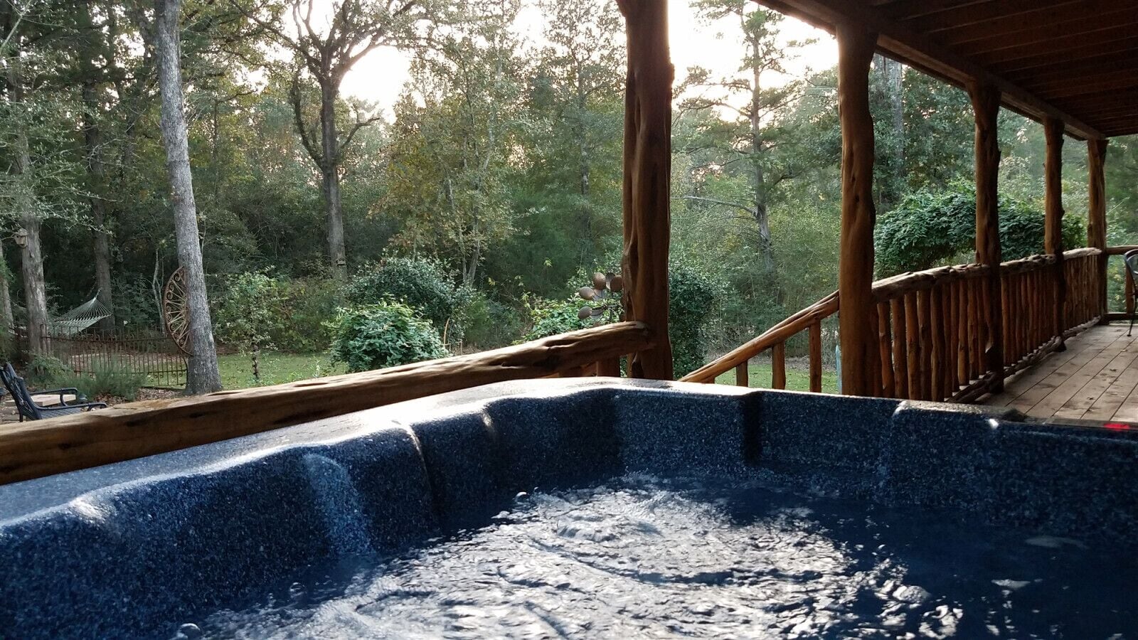 Un jacuzzi con una terraza de madera y vistas a una zona boscosa.