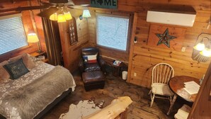 Ein gemütliches Blockhauss-Interieur mit einem Bett, einem Sessel, einem Tisch, einer Lampe und einem Schild mit der Aufschrift 'HOME'.