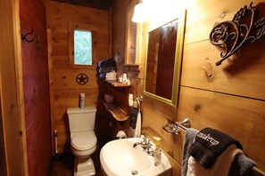 Un bagno in legno compatto con il water, un lavabo e uno specchio.