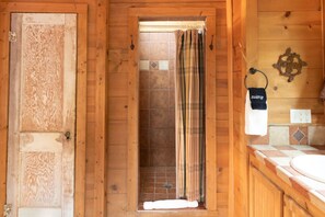 A wooden cabin bathroom with a shower, a towel rack, and a sink.