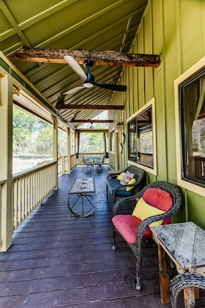 A covered porch with a table and chairs, a ceiling fan, and a view of the outdoors.