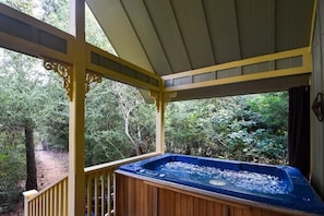 Un jacuzzi en una terraza de madera con vista a un área boscosa.