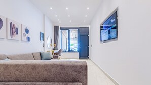 Una sala de estar moderna con un sofá, un escritorio y un televisor montado en la pared.