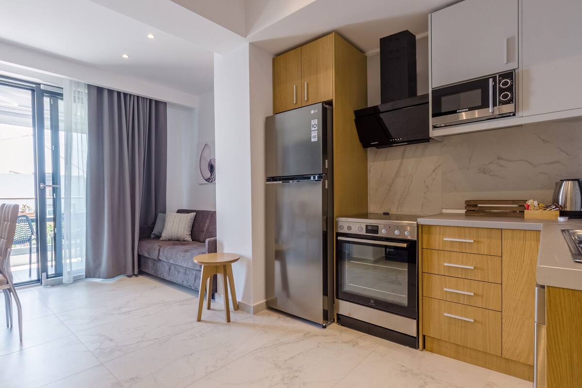 Eine moderne Küche mit Einbauofen, Mikrowelle und Kühlschrank. Ein Essbereich mit Tisch und Stühlen sowie eine Sitzecke mit Sofa vorhanden.