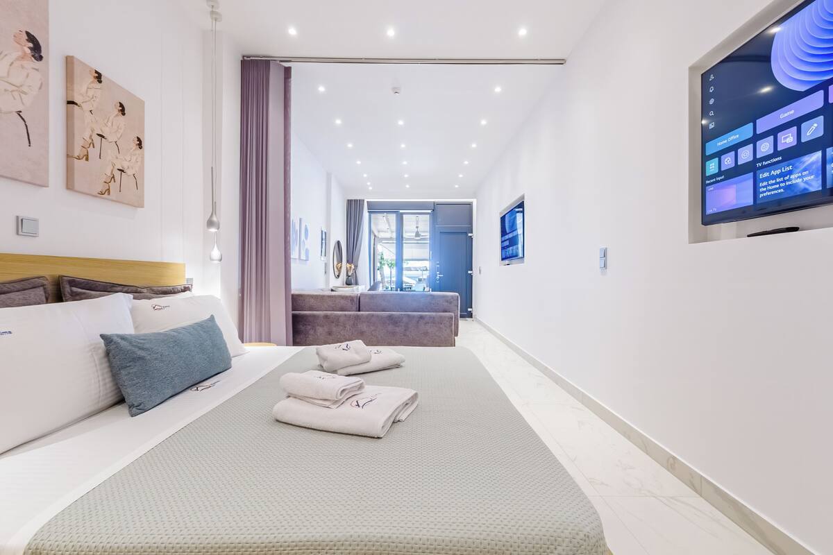 Ein modernes Hotelzimmer mit einem großen Bett, einem Fernseher und Kunstwerken an den Wänden.