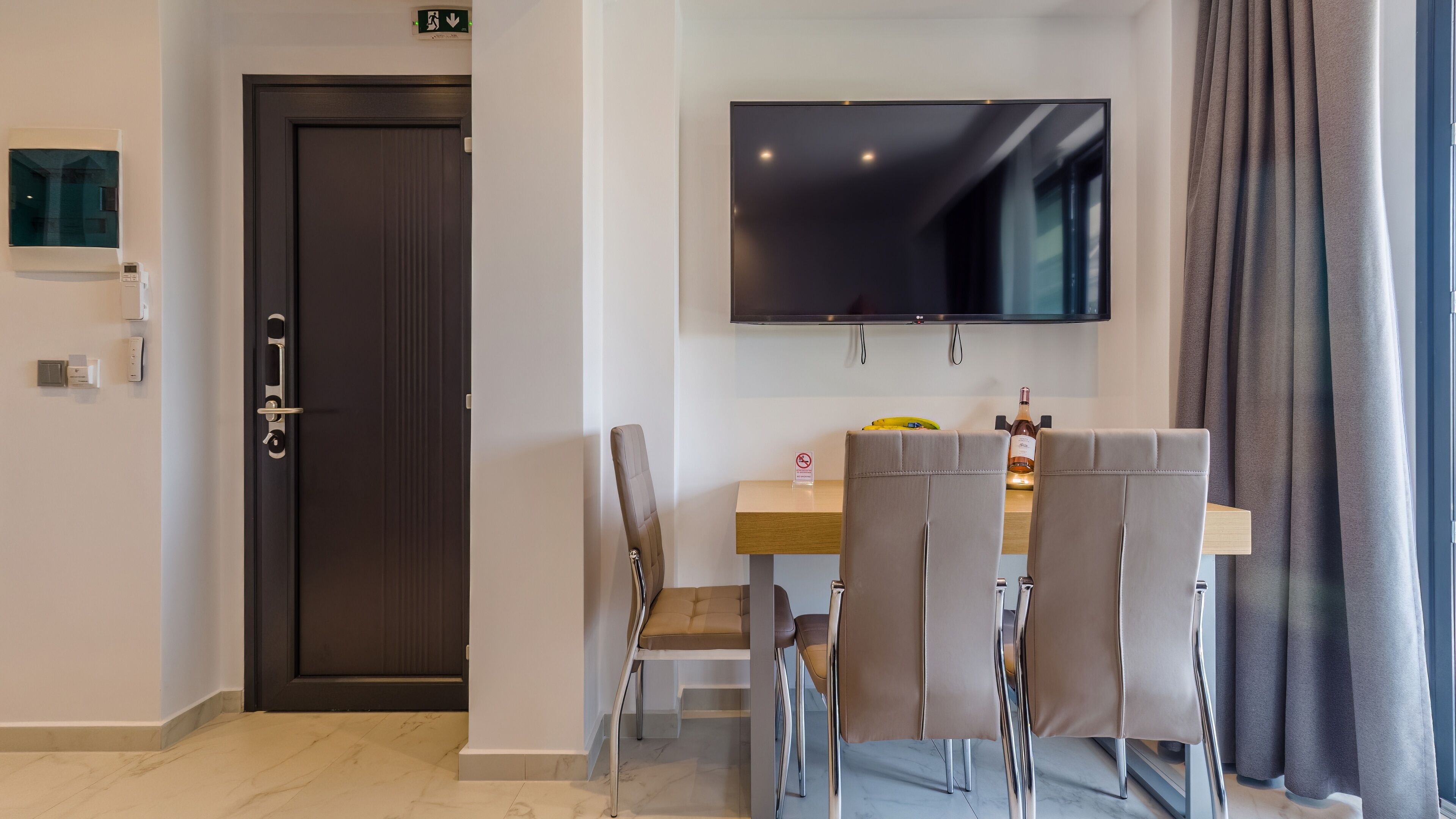 A modern dining area with a TV, a door, and a table with chairs.