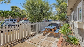 A backyard with a barbecue grill, picnic table, and a white picket fence. - Beach Bungalow Parking 2blocks to Beach (San Diego)