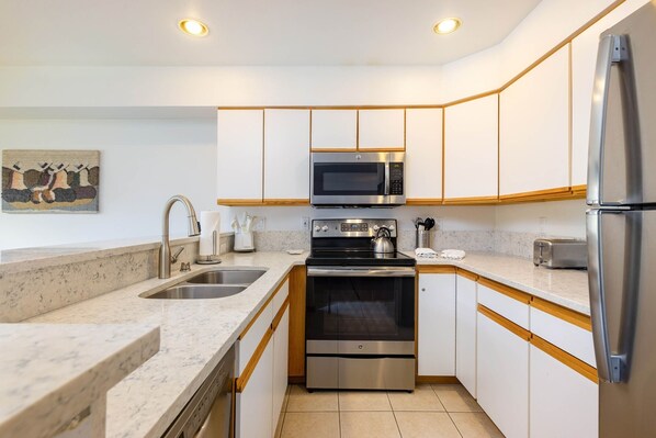 A modern kitchen with a stainless steel refrigerator, microwave, stove, and oven.