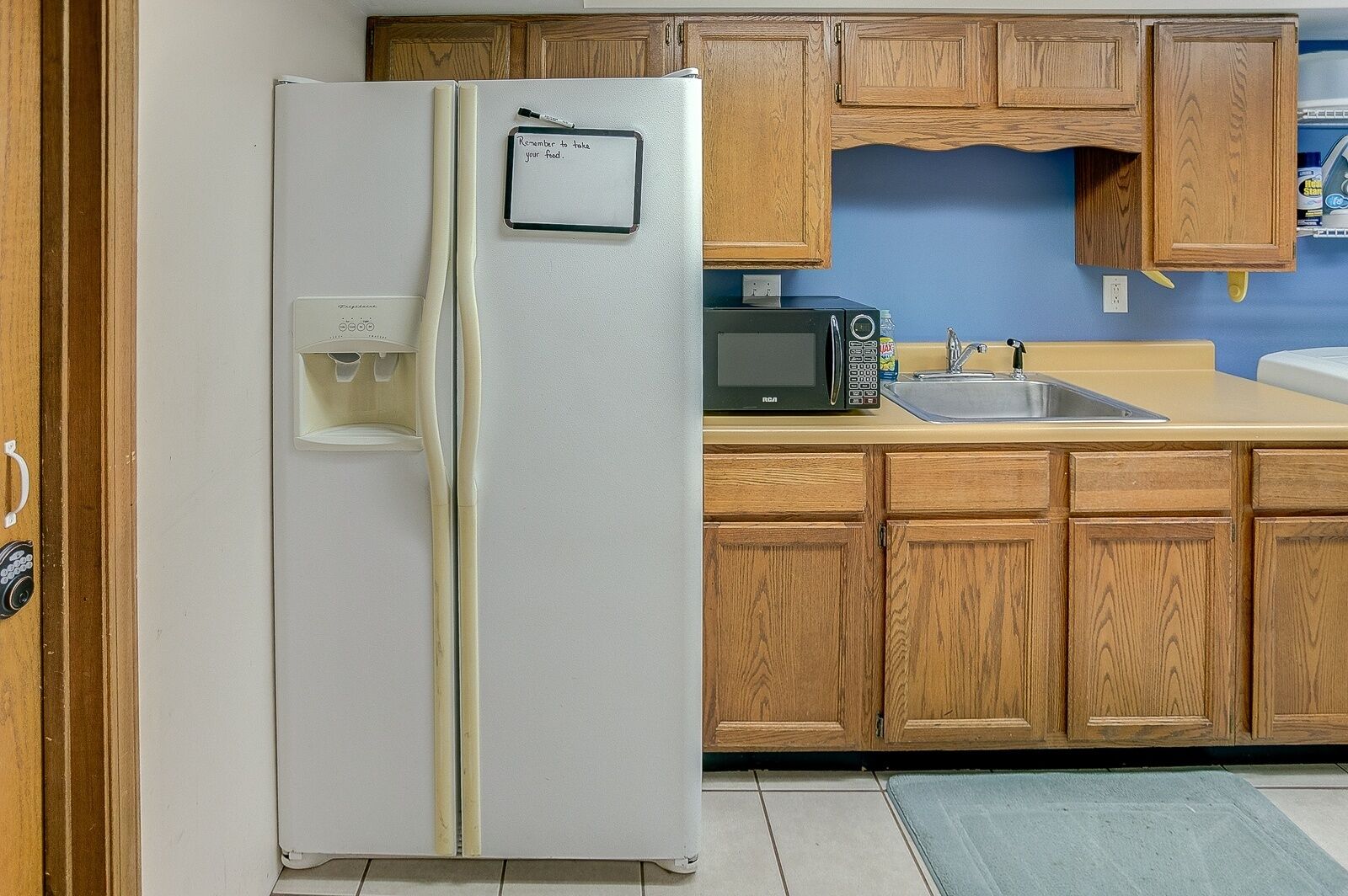 A kitchen with a white refrigerator, wooden cabinets, a microwave, and a sink.
